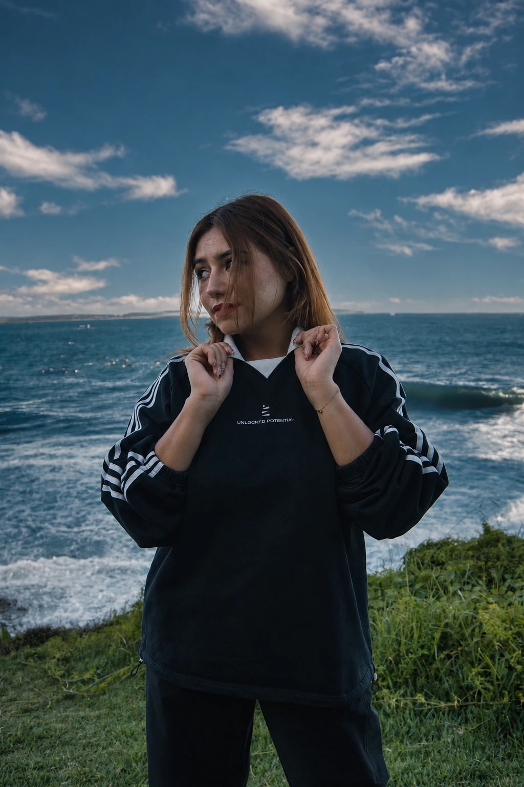 Mayte holding the collar of her DIV3NITY jersey beside the ocean