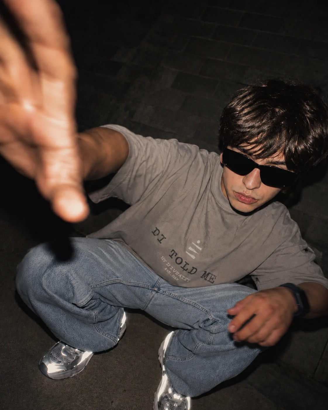 DIV3NITY model wearing a graphic tee and dark sunglasses